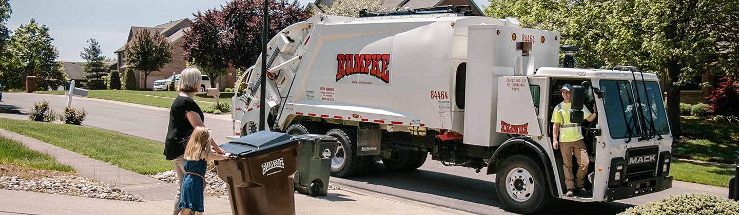 Garbage truck driver picking up trash and recycling from neighborhood