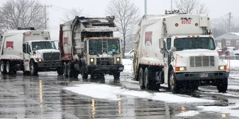 Three Rumpke Trucks Driving In A Snow Storm And Poor Winter Conditions